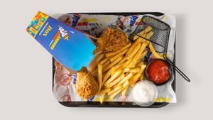 Top view of fried chicken, fries, and sauces served in a fast food tray.