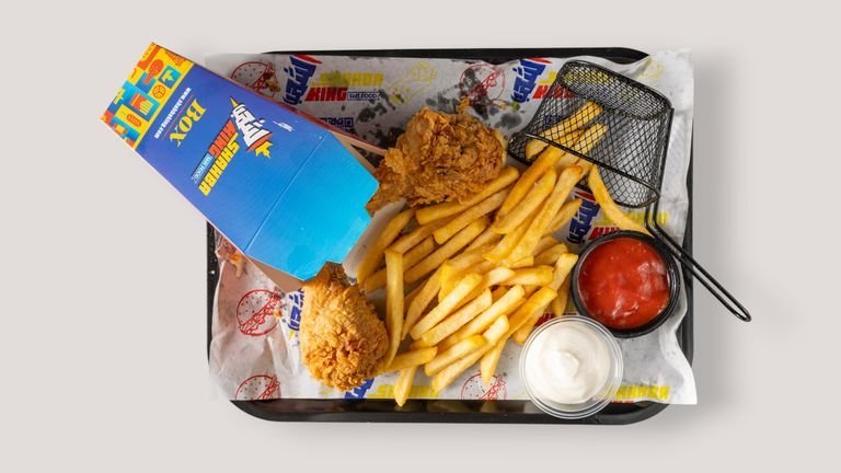 Top view of fried chicken, fries, and sauces served in a fast food tray.