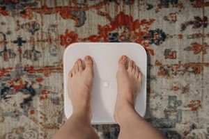 Overhead view of feet on a smart scale atop a decorative carpet, focusing on balance and health.